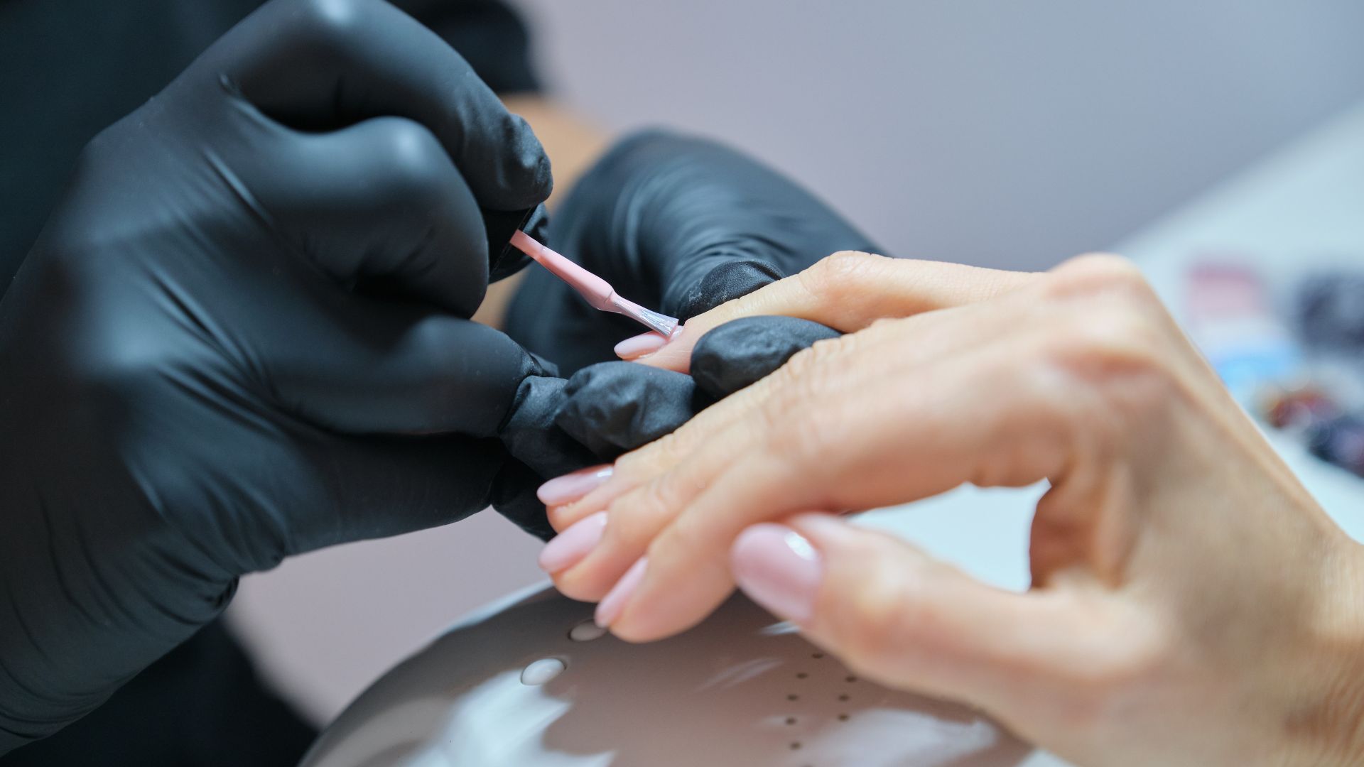 Macro detail of a nail technician finishing a nail