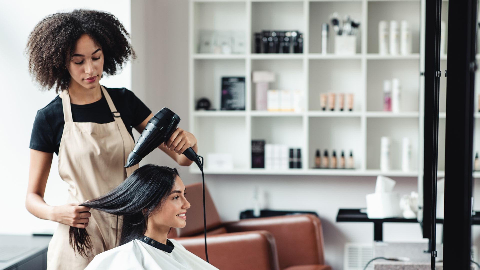 Stylist blow-drying and shaping a client's hair at the chair