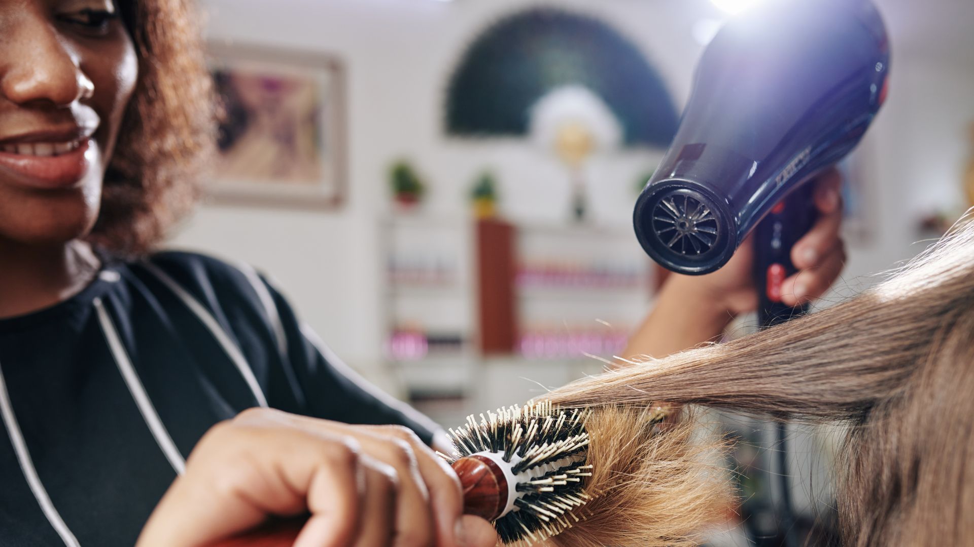 Close detail of a round brush and dryer working through sectioned hair
