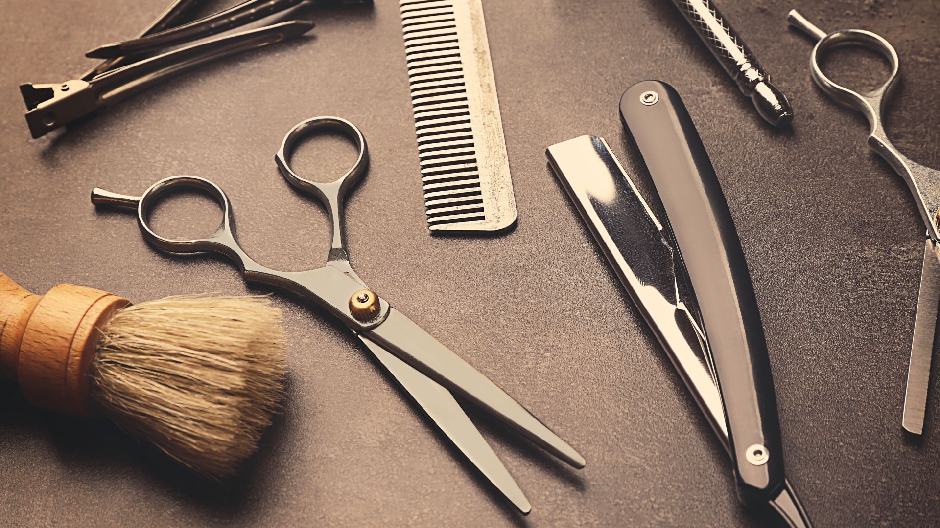 Flat-lay of salon shears, comb and razor in a leather roll
