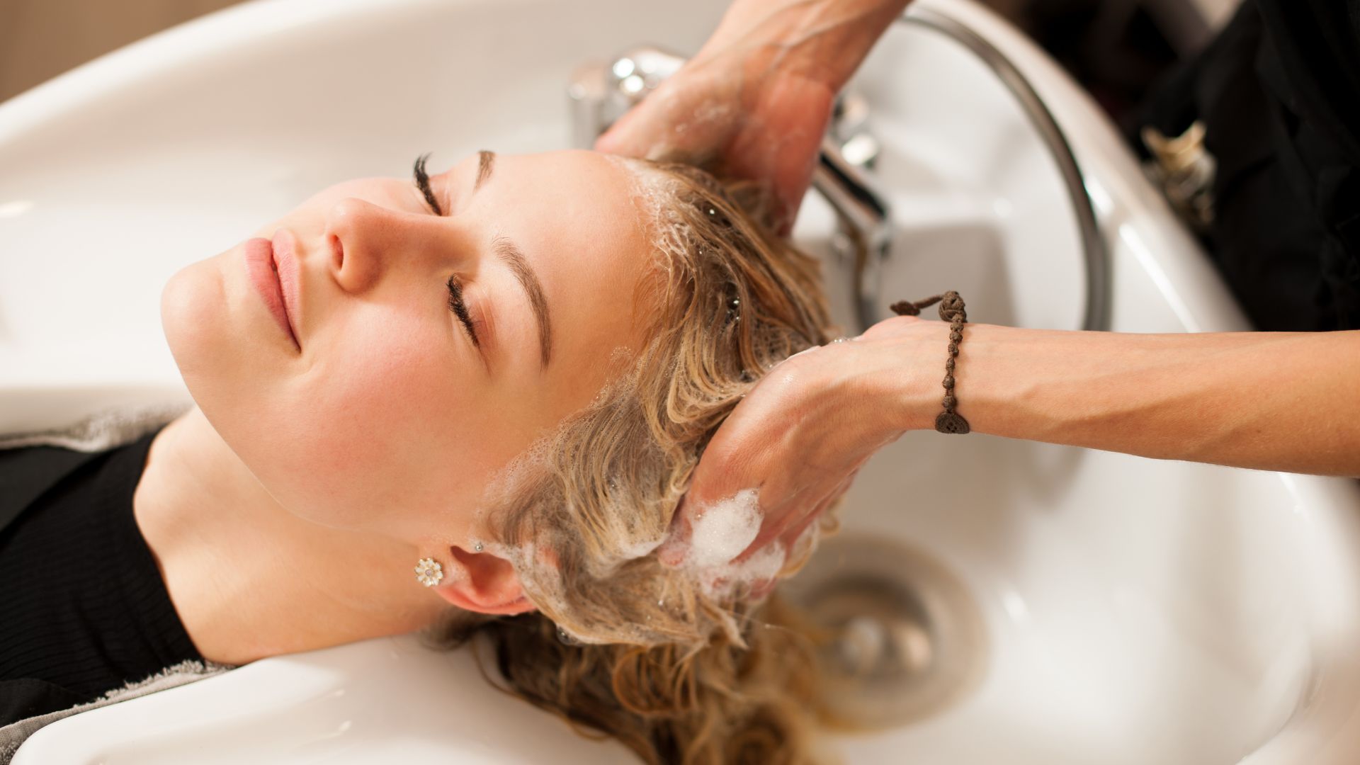 Shampoo and lather being worked through hair at the basin